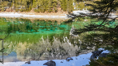Winter landscape of Austrian Alps with Green Lake in the middle. Powder snow covering the mountains and ground. Emerald color of water. Soft reflection of Alps in calm lake's water. Winter wonderland