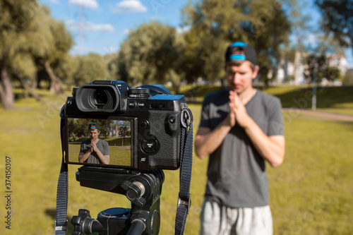A man records video with a camera outdoors in a park. Distance lifestyle concept. Online communication, consultations, training, business.