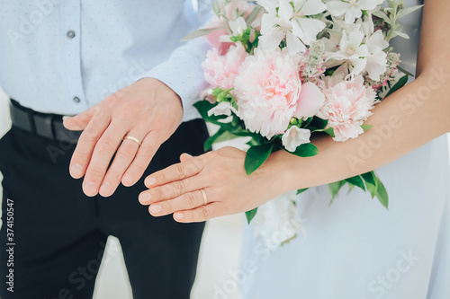 Hands of newlyweds with wedding rings. The bride is holding a wedding bouquet. Wedding.
