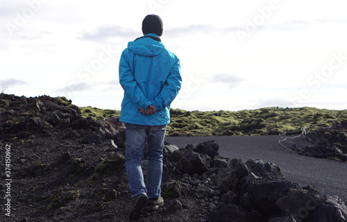 Asian man jiking in Iceland wearing blue outdoor jacket in Summer