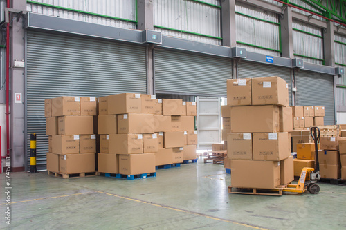 The forklift loading shipment carton boxes and goods on wooden pallet at loading dock from container truck to warehouse