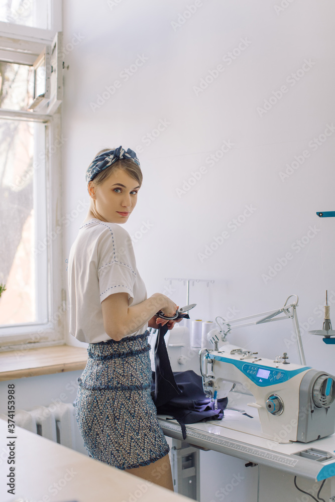 Young attractive woman working as fashion designer with sewing machine in studio. Small business, self-employed women concept. Young attractive woman working as fashion designer with sewing machine in studio. Small business, self-employed women concept.