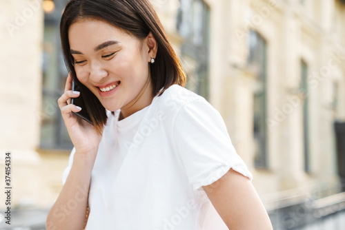 Happy young asian woman talking by mobile phone