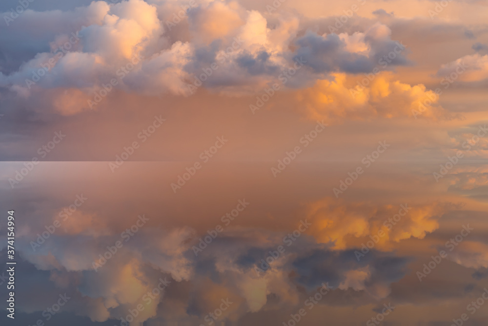 Magical pale pink sky with fluffy colorful clouds at sunset and the sea