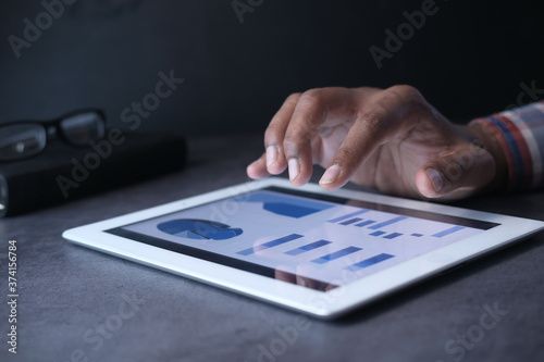 man's hand working on digital tablet at office desk, using self created chart 