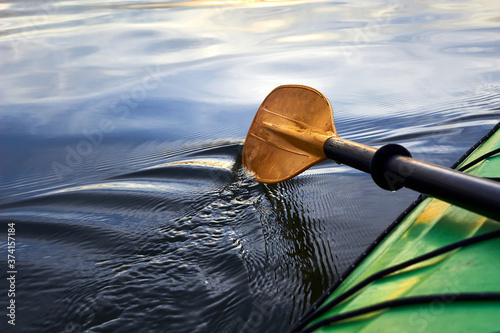 Bilde på lerret Boat oar and part of green kayak in the water and splashing water at evening riv