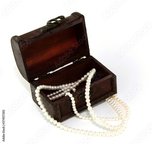 Numerous spherical pearls, lined up into necklaces, placed in antique wooden boxes on a white background.