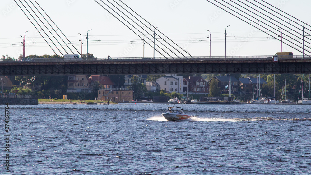 Obraz premium Riga. Daugava river. Cable-stayed bridge. Fast boat on the river.