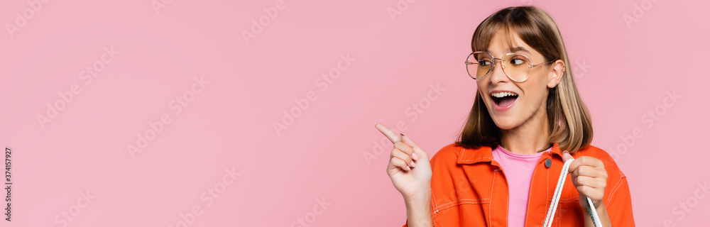 Horizontal crop of young woman in sunglasses pointing with finger isolated on pink - obrazy, fototapety, plakaty 