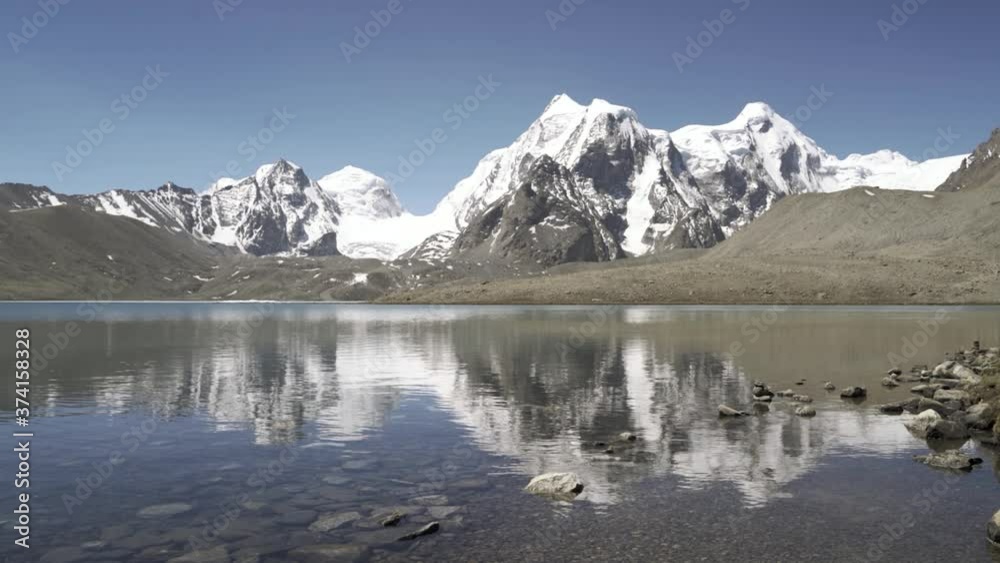 Landscape Of Gurudongmar Lake With Reflections Of Snowy Himalayas On The Calm Water In Sikkim, India. The Second Highest Lake In India - wide shot Landscape Of Gurudongmar Lake With Reflections Of Snowy Himalayas On The Calm Water In Sikkim, India. The Second Highest Lake In India - wide shot