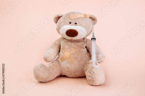 Stuffed Bear animal with syringe isolated on pink background. Children doctor theme.