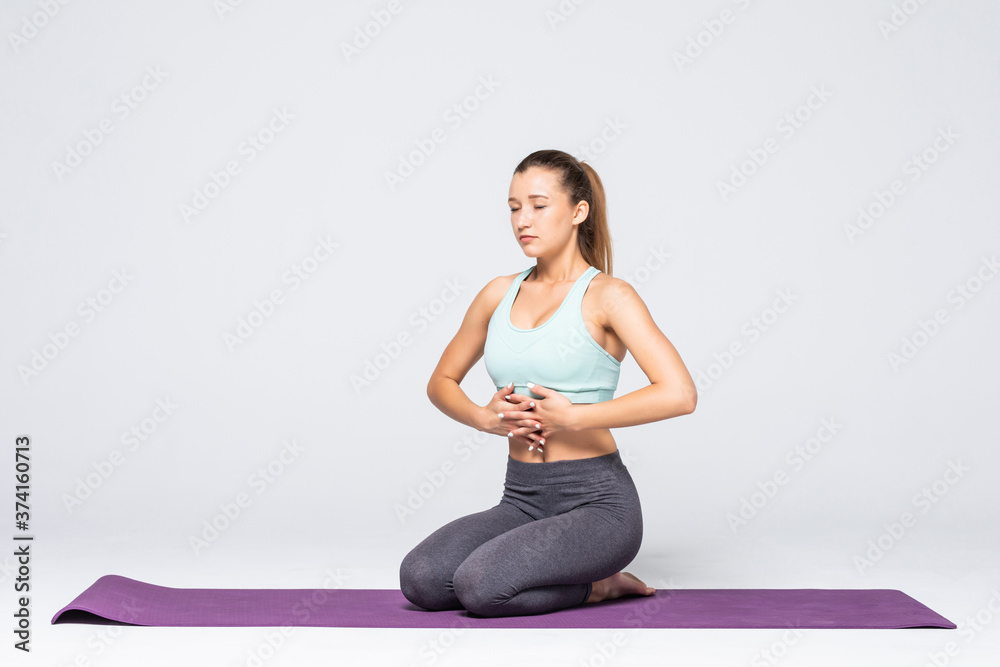 Portrait of pretty young woman doing yoga exercise meditation on mat isolated on white background Portrait of pretty young woman doing yoga exercise meditation on mat isolated on white background