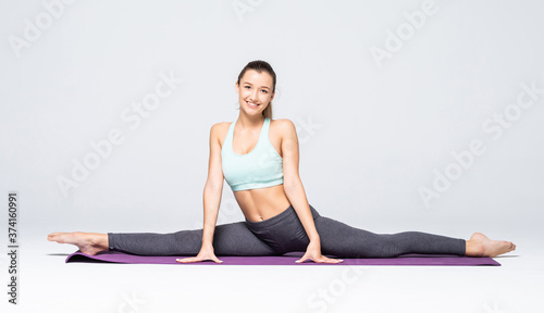Young woman practicing yoga twine poses isolated on white background © dianagrytsku