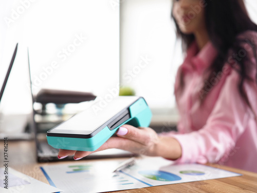 Girl in workplace holds banking mobile device photo