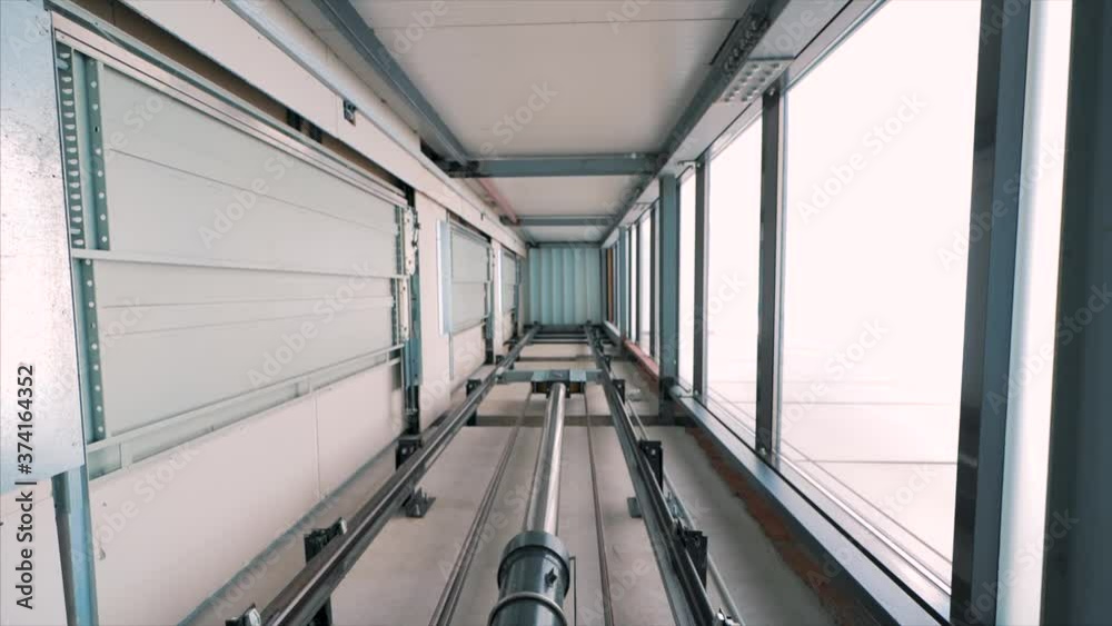 Elevator lift cabin moves up inside illuminated elevator shaft with hydraulics with many floors slow motion