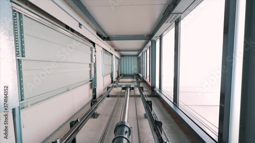 Elevator lift cabin moves up inside illuminated elevator shaft with hydraulics with many floors slow motion photo