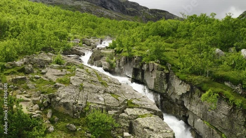 Water Cascading And Flowing Over The Hydalen Stream By The Mountian Pass In Hemsedal, Norway.  - low aerial drone shot photo