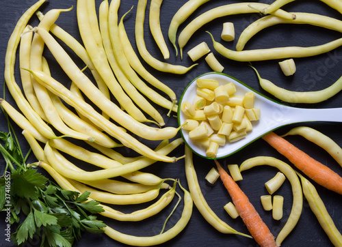 Freshly harvested yellow runner beans and spoon with chopped beans on stone. Top view, ingredient healthy eating