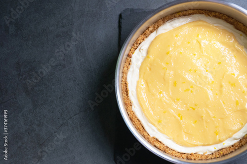 Delicious homemade honey lemon cheese pie and juicy lemon curd in a mold on black table background.