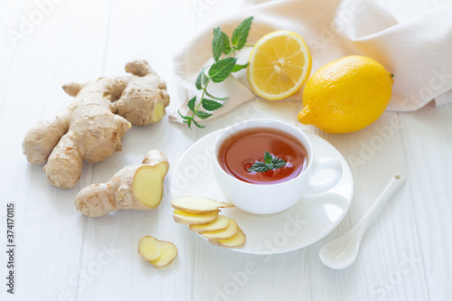 Antiviral ginger tea with lemon and mint on white wooden background
