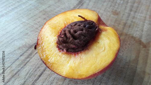 Peach cut in half on a wooden table. Delicious fruit. Vegan food.