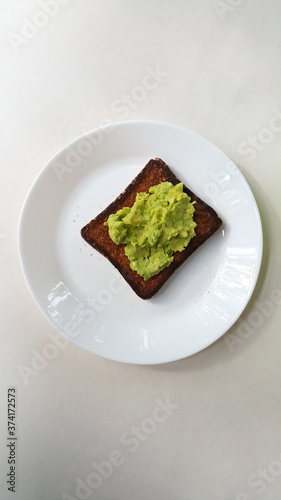 Baked toast with avocado on a white plate. Vegan food. 