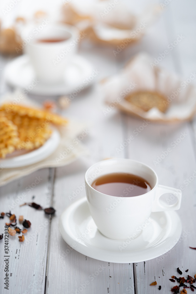 Cup of fresh herbal tea placed on wooden table near snacks for breakfast in morning Cup of fresh herbal tea placed on wooden table near snacks for breakfast in morning