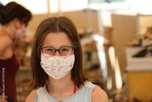 girl smiles with a surgical mask while shopping in the local mar