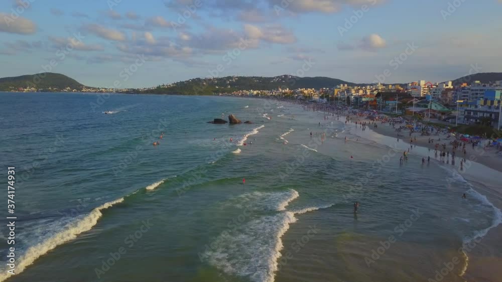 Aerial shot flying over sea waves alongside Bombas beach in Brazil at golden hour Aerial shot flying over sea waves alongside Bombas beach in Brazil at golden hour