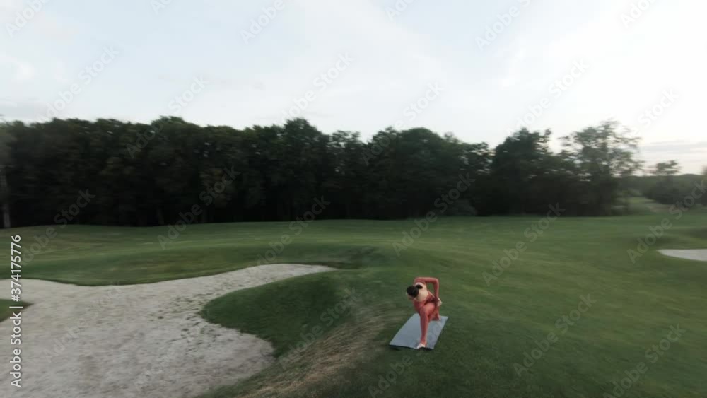 Creative aerial shot with fpv racing drone of woman in red tracksuit doing yoga in the park at sunny day at sunset. Creative aerial shot with fpv racing drone of woman in red tracksuit doing yoga in the park at sunny day at sunset.