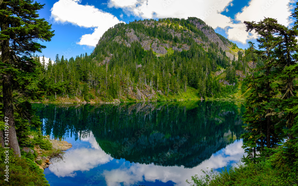 A clear alpine lake with a mountain in the background and reflections on the water