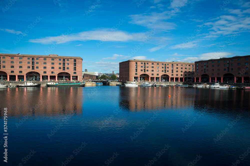 View across calm water in a harbour to old dock buildings in Liverpool
