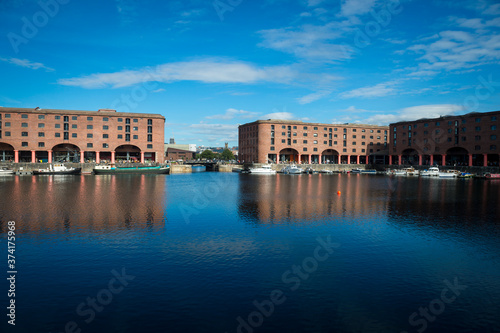 View across calm water in a harbour to old dock buildings in Liverpool