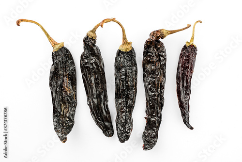 Dried Mexican black hot Chile Pasilla chili offered as close-up on white background with copy space - free-form select photo