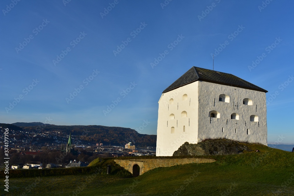 old fortress in the mountains. kristiansten fortress in trondheim city norway. the white tower against bluesky and meadow  surround with the mountain and city
