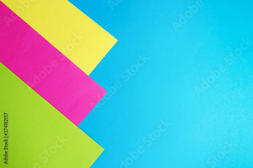 abstract background pink, yellow and green paper on blue.. copy space.