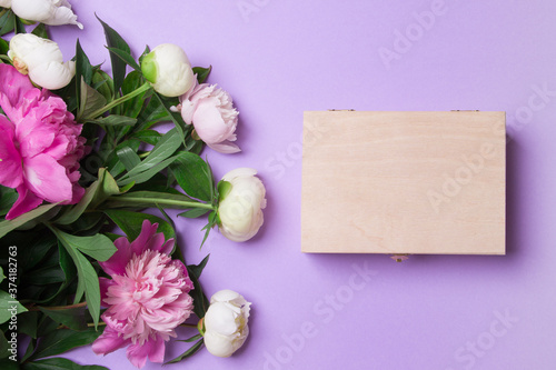 bouquet of pink and white peony and closed wooden box on purple background