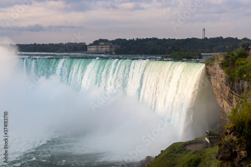 Wide shot of Niagara Falls Horseshoe Falls with early morning sun rays and overcast sky