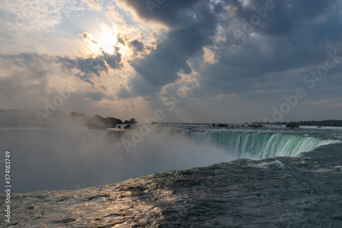 Niagara Falls Horseshoe Falls with early morning sun rays shining through overcast sky