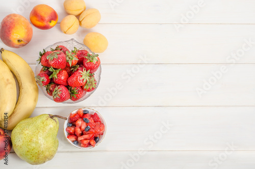 Fresh strawberries with fruits on a white background with copy space. Ingredients for fruit salad.