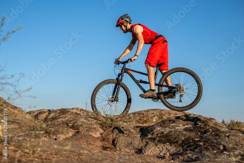 A cyclist rides over stones against a blue sky, copy of the free space. Active lifestyle, cycling.