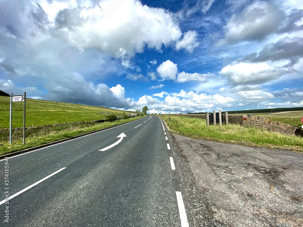 The A6068 Colne to Cowling road, with broken cloud, and green fields near, Cowling, Keighley, UK