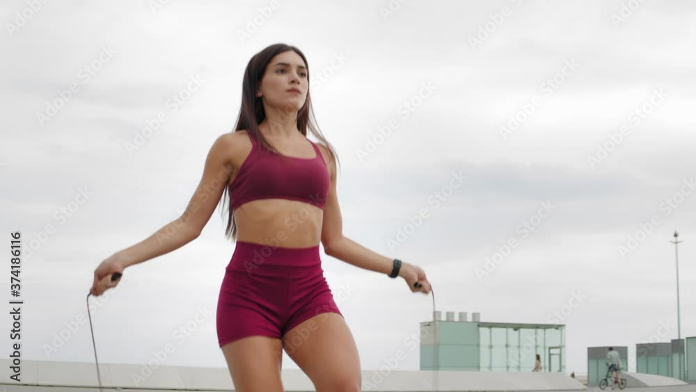Portrait of fit young woman with jump rope in a park. Fitness female doing skipping workout outdoors on a sunny day. Latin american student, hispanic girl on training Portrait of fit young woman with jump rope in a park. Fitness female doing skipping workout outdoors on a sunny day. Latin american student, hispanic girl on training