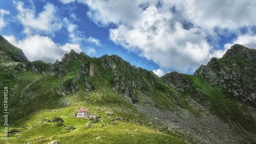 House on hill between mountains with clouds shadow cast and blue sky beautiful landscape travel Lacul Balea Transfagarasan