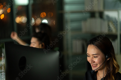 employee customer service representative working as technical support call center in the office with headphone computer overtime in the night