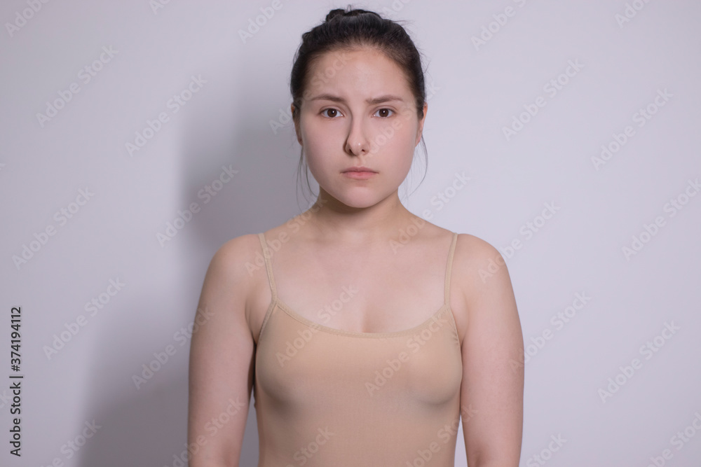 Obraz premium emotional portrait of attractive brunette, actress in a beige undershirt - bodysuit on white background. space for text. High quality photo