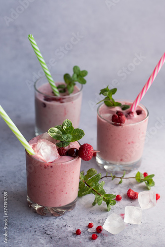 Glasses of berry smoothie with fresh mint on dark background.