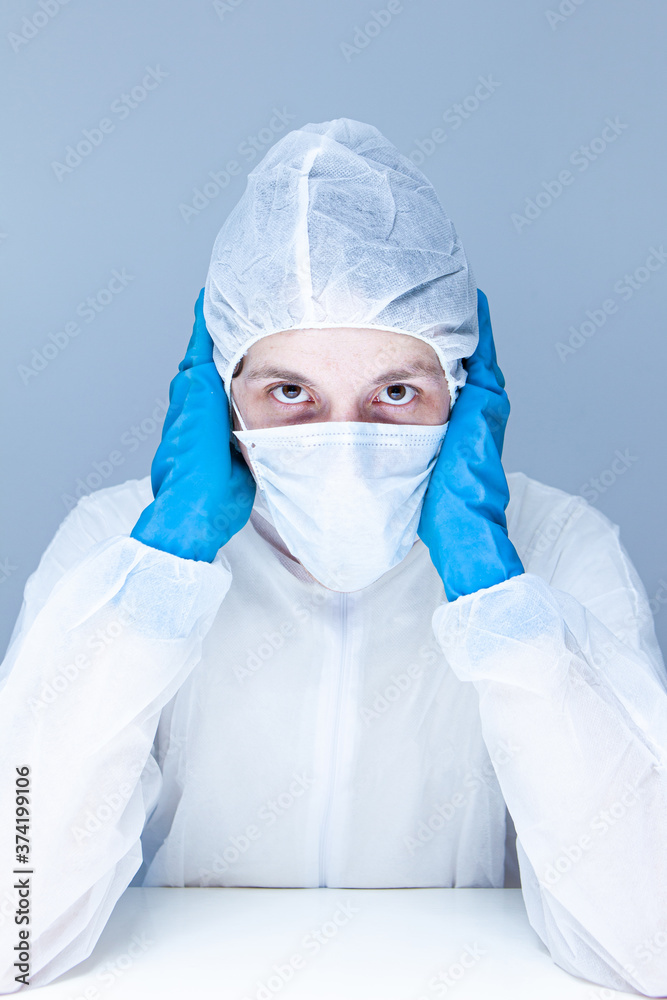 man in protective suit, gloves and mask on his face holding his head pretending to panic or fear. The concept of health. man in protective suit, gloves and mask on his face holding his head pretending to panic or fear. The concept of health.