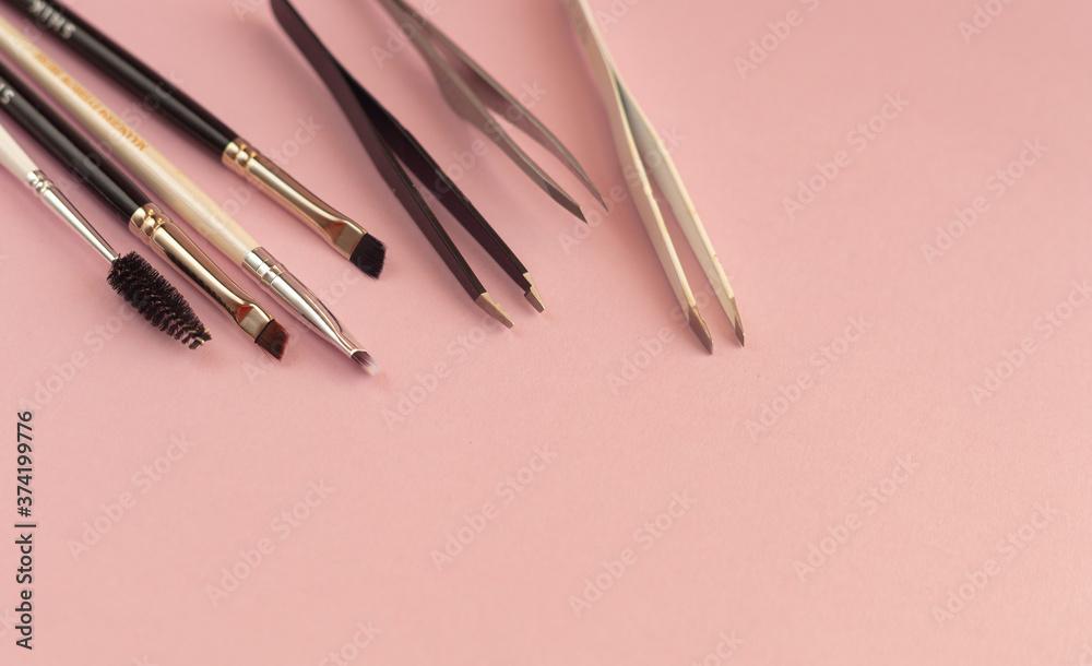 Eyebrow shaping tools, tweezers, brushes on pink background Eyebrow shaping tools, tweezers, brushes on pink background