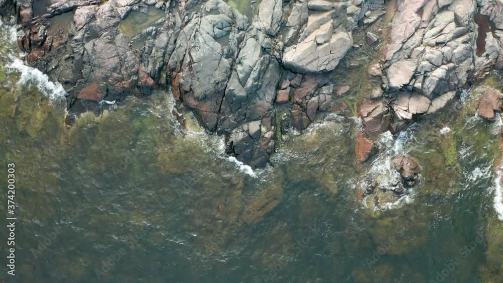 Rotating aerial view of waves hitting a rocky beach Rotating aerial view of waves hitting a rocky beach